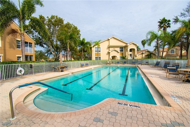 community pool with a patio area and fence