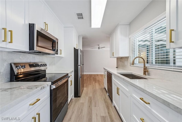 1196 Westlake Blvd, Naples, FL 34103 - kitchen featuring decorative backsplash, white cabinetry, a sink, light wood-style flooring, and appliances with stainless steel finishes