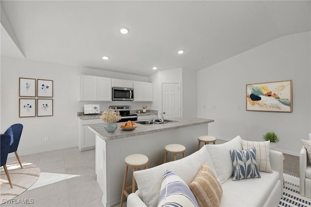 kitchen with a breakfast bar area, recessed lighting, white cabinets, a sink, and stainless steel appliances