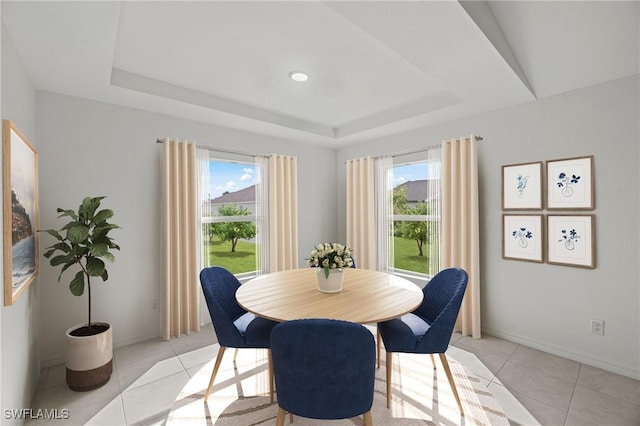 dining room featuring a healthy amount of sunlight, light tile patterned floors, baseboards, and a tray ceiling