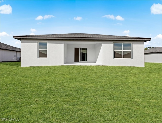 back of property with a lawn and stucco siding