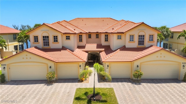 mediterranean / spanish-style house featuring a tiled roof, stucco siding, and decorative driveway