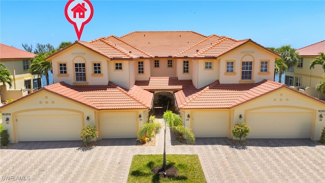 mediterranean / spanish-style house featuring decorative driveway, a tile roof, and stucco siding