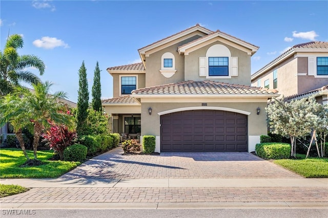 mediterranean / spanish-style home featuring a garage, stucco siding, driveway, and a tile roof