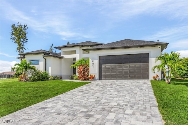 prairie-style house with stucco siding, decorative driveway, a front yard, and a garage