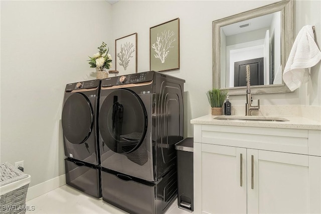 laundry area with baseboards, a sink, cabinet space, and washing machine and dryer