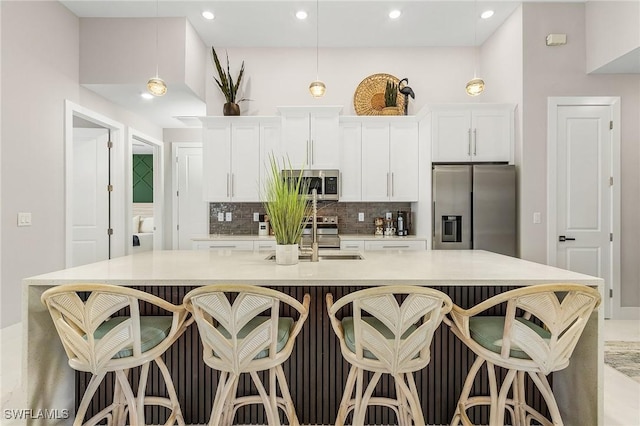 kitchen featuring decorative backsplash, a large island, white cabinets, a sink, and appliances with stainless steel finishes