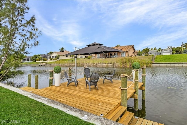 view of dock featuring a gazebo, a water view, a lawn, and a residential view