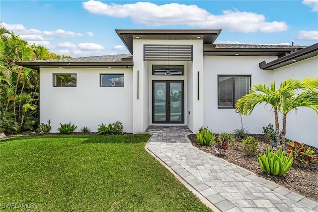 property entrance featuring a lawn, french doors, and stucco siding