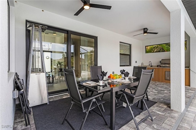 view of patio with grilling area, a ceiling fan, outdoor dining space, and exterior kitchen