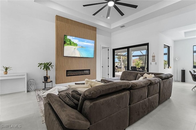 living room featuring visible vents, a raised ceiling, ceiling fan, and concrete floors