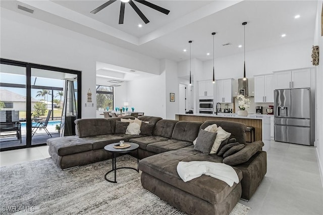 living room with a ceiling fan, visible vents, light tile patterned floors, a high ceiling, and recessed lighting