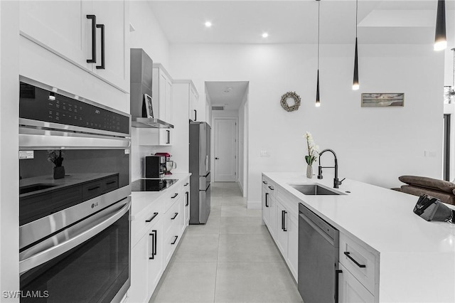 kitchen with white cabinetry, a sink, light countertops, stainless steel appliances, and wall chimney exhaust hood