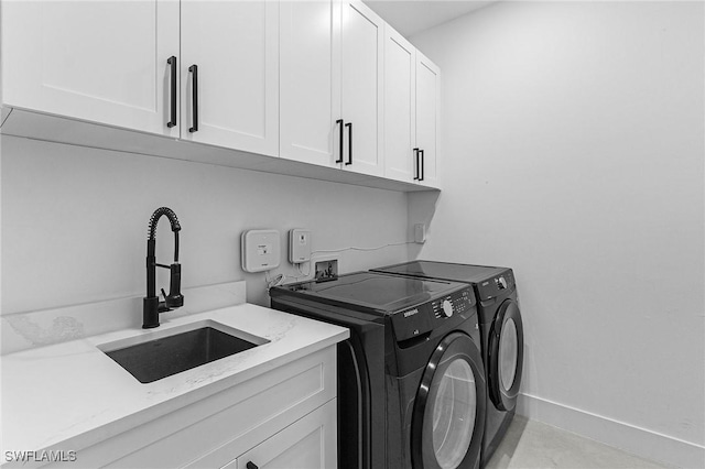 laundry area featuring cabinet space, baseboards, a sink, and washer and clothes dryer