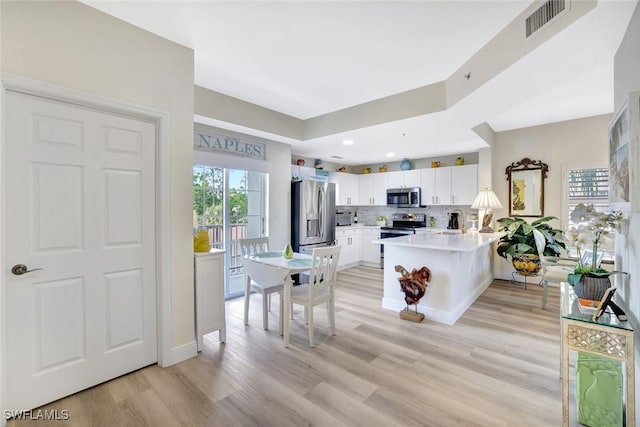 4500 Botanical Place Cir Unit 301, Naples, FL 34112 - kitchen with appliances with stainless steel finishes, light wood finished floors, a peninsula, decorative backsplash, and visible vents