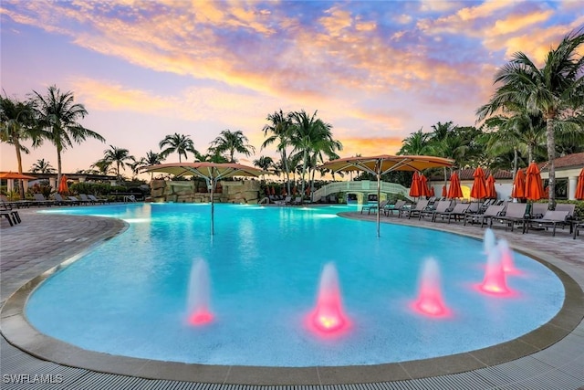 pool at dusk with a patio and a community pool
