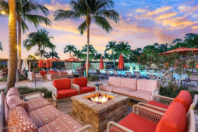 view of patio with a community pool and an outdoor living space with a fire pit