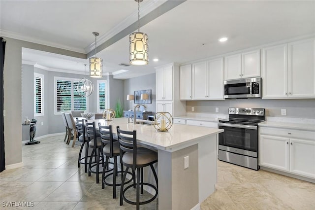 kitchen featuring ornamental molding, an island with sink, white cabinets, a sink, and appliances with stainless steel finishes