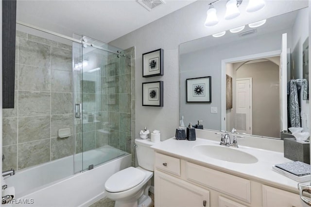 full bathroom featuring toilet, visible vents, bath / shower combo with glass door, and vanity