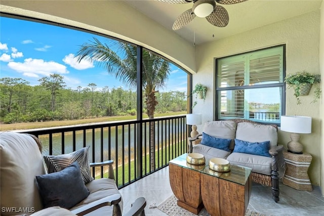 sunroom featuring a ceiling fan, outdoor lounge area, and a water view