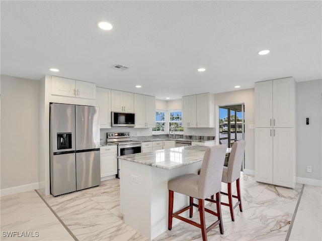 kitchen with appliances with stainless steel finishes, light marble finish floors, light stone countertops, recessed lighting, and white cabinetry
