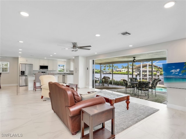 living room featuring a ceiling fan, recessed lighting, light marble finish flooring, healthy amount of natural light, and baseboards