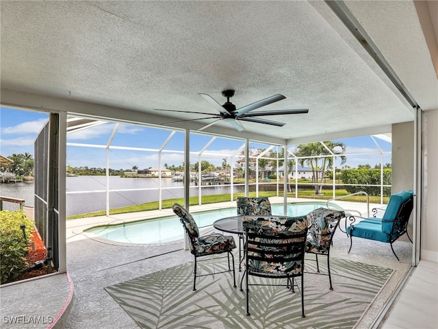 sunroom / solarium featuring a swimming pool, ceiling fan, and a water view