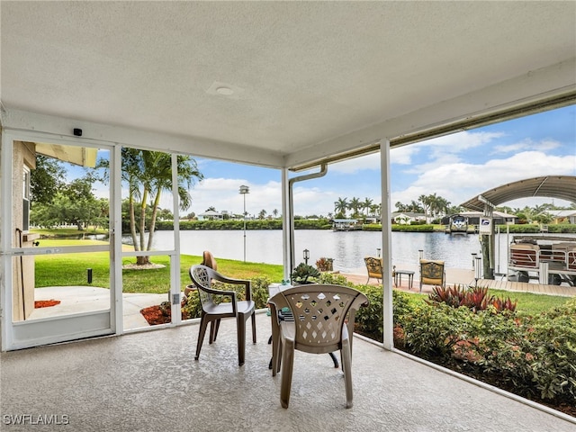 sunroom / solarium with a textured ceiling, a water view, and carpet floors