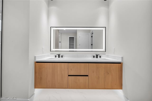 bathroom with double vanity, baseboards, a sink, and marble finish floor