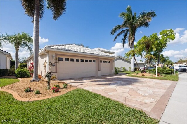 20849 Santorini Way N, Fort Myers, FL 33917 - view of front of house with concrete driveway, an attached garage, a tile roof, and stucco siding