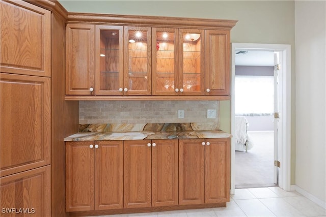 20849 Santorini Way N, Fort Myers, FL 33917 - kitchen featuring backsplash, baseboards, brown cabinetry, and glass insert cabinets