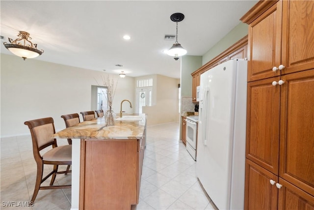 20849 Santorini Way N, Fort Myers, FL 33917 - kitchen featuring a sink, white appliances, a breakfast bar area, an island with sink, and visible vents