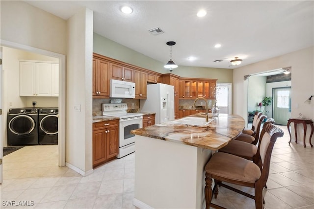 20849 Santorini Way N, Fort Myers, FL 33917 - kitchen featuring brown cabinetry, visible vents, white appliances, separate washer and dryer, and a sink