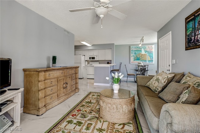 living room with a textured ceiling, marble finish floor, and ceiling fan