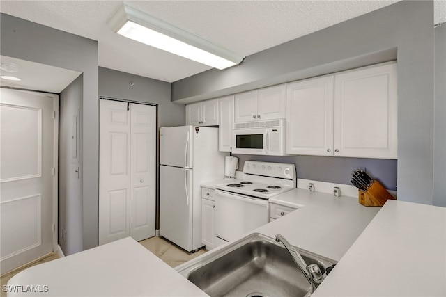 kitchen featuring white appliances, light countertops, a textured ceiling, white cabinets, and a sink