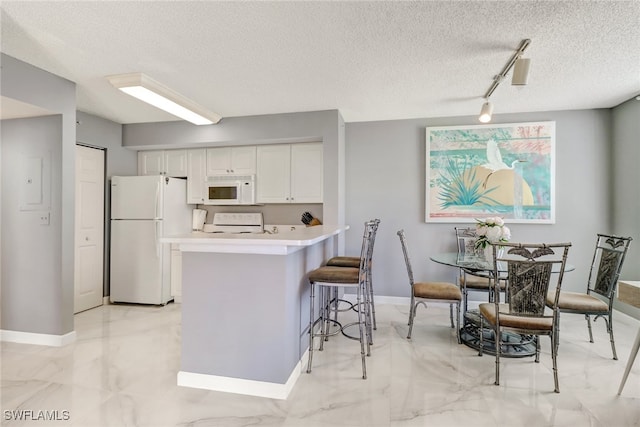 kitchen featuring a textured ceiling, track lighting, white cabinets, marble finish floor, and white appliances