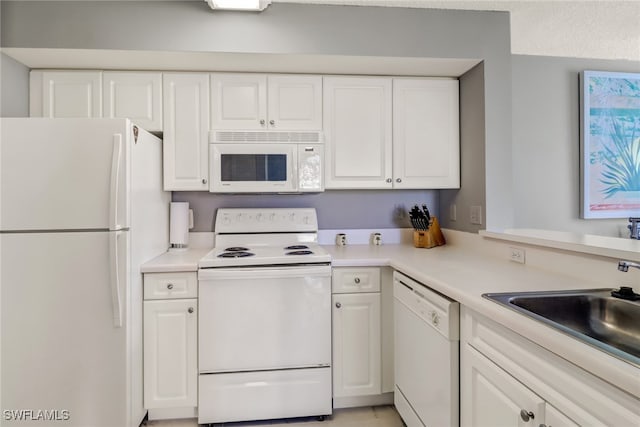 kitchen featuring white appliances, white cabinetry, a sink, and light countertops