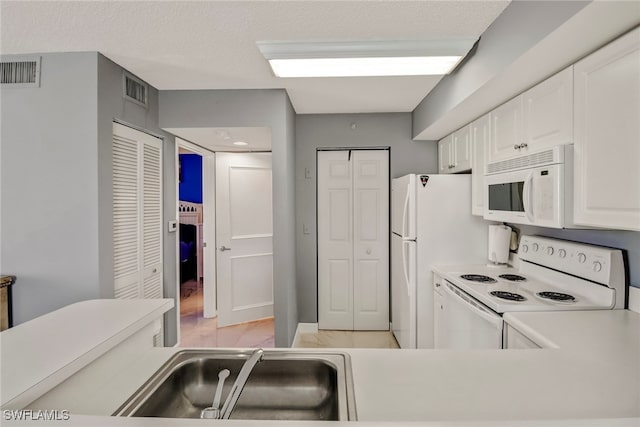 kitchen with visible vents, light countertops, white cabinets, and white appliances