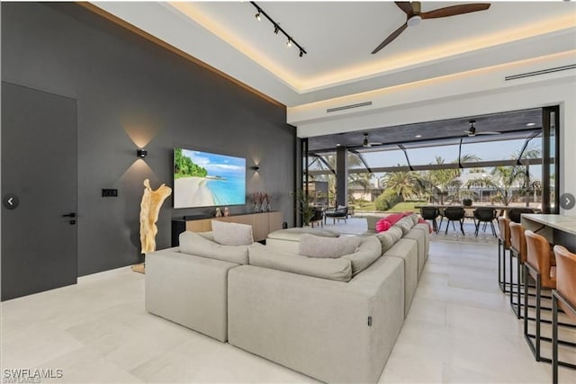 living area with a ceiling fan, a raised ceiling, a sunroom, and rail lighting
