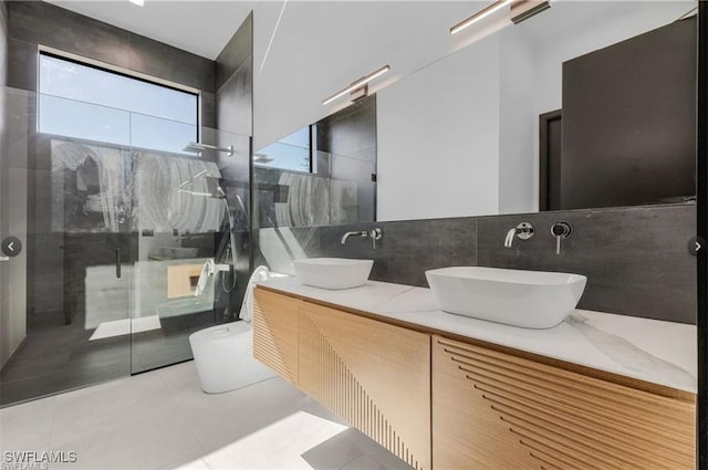 bathroom featuring a sink, a shower stall, tile patterned floors, and tile walls