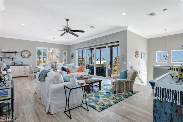 living room featuring crown molding, ceiling fan with notable chandelier, light wood finished floors, and visible vents