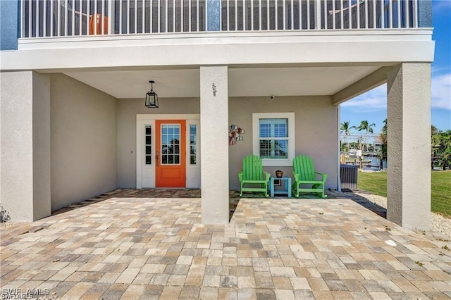 property entrance with stucco siding, a patio area, and a carport