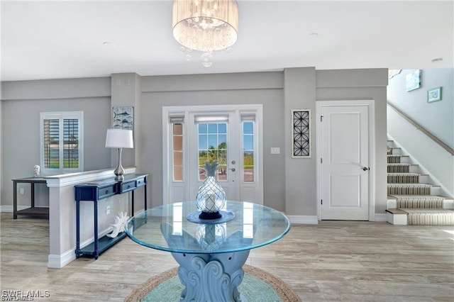 dining space with baseboards, wood finished floors, a notable chandelier, and stairway