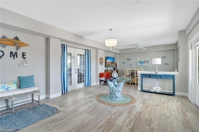 living area with baseboards, ceiling fan, french doors, and wood finished floors