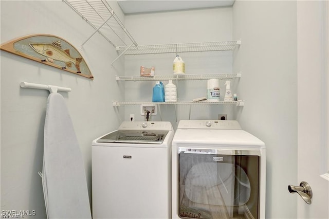 clothes washing area featuring separate washer and dryer and laundry area
