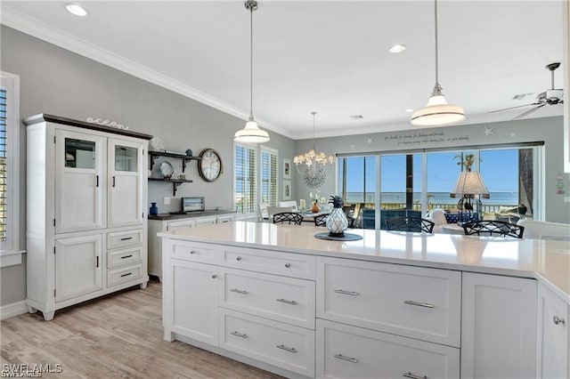 kitchen featuring light countertops, ornamental molding, white cabinetry, and decorative light fixtures