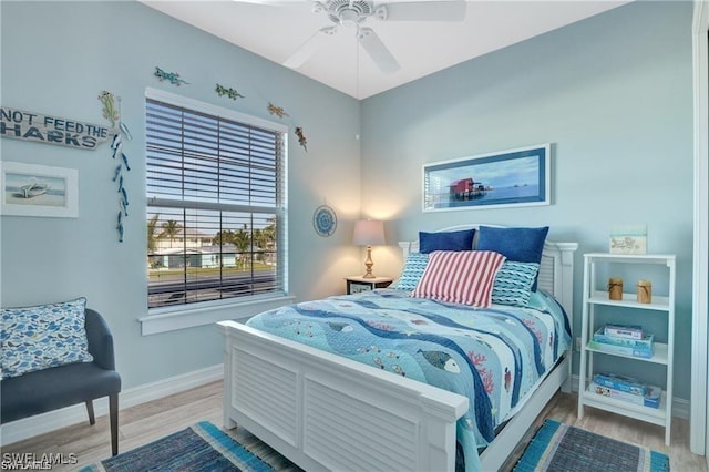 bedroom with baseboards, a ceiling fan, and light wood-style flooring