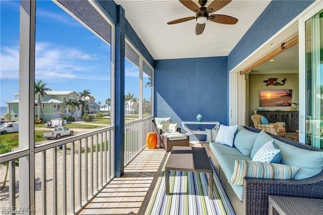 sunroom with a residential view, a ceiling fan, and outdoor lounge area
