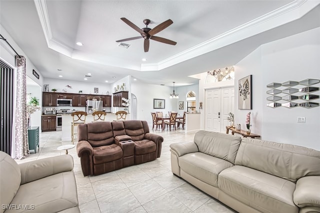 living room featuring recessed lighting, a tray ceiling, ornamental molding, and ceiling fan with notable chandelier