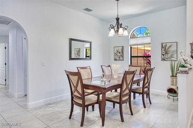 dining space featuring a notable chandelier, arched walkways, baseboards, light tile patterned floors, and visible vents